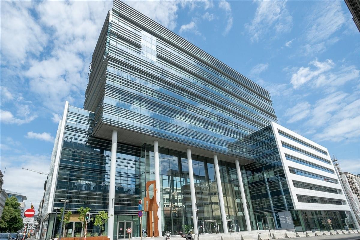 Modern glass and steel exterior of the Rue Belliard 40 building under a blue sky.