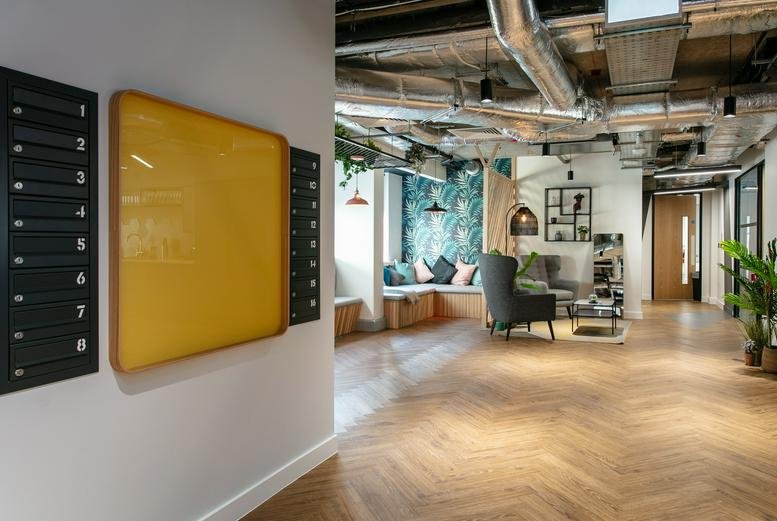 Spacious communal lounge with herringbone wood flooring and exposed ceiling pipes at Temple Meads, 101 Victoria St.