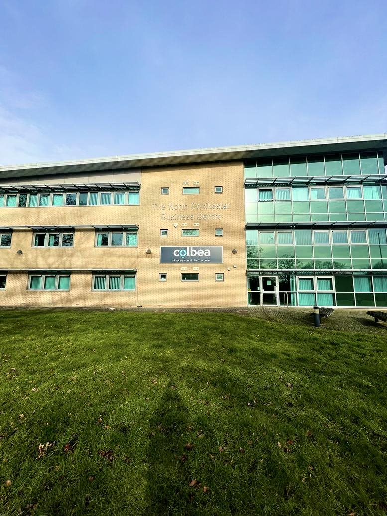 Exterior view of the contemporary glass-fronted building and manicured lawn.