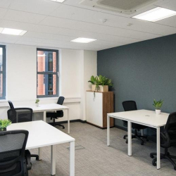 Private office suite with white desks, ergonomic black chairs, and a dark grey feature wall.