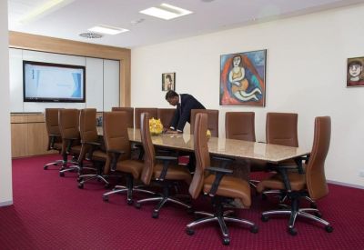 Professional boardroom with leather chairs, long table, and colorful abstract wall art.