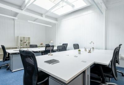Spacious open-plan office with white desks, ergonomic black chairs, and a skylight.