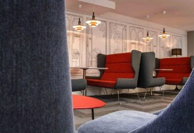 Breakout area with high-backed red and grey seating pods and designer lamps.