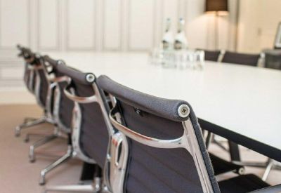 Bright boardroom with white table, grey chairs, and red pendant lights.