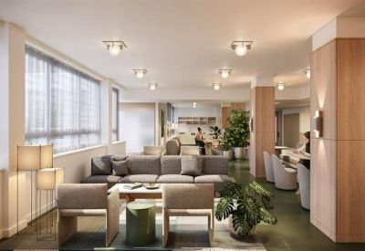 Modern lounge area featuring grey sofas, potted plants, and warm wood-paneled pillars.