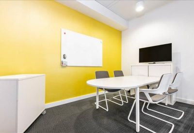 Small meeting room with a yellow accent wall, whiteboard, and television.