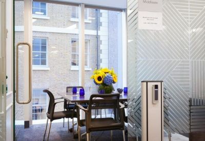 Private meeting room with a wooden table, blue accents, and views of surrounding brick buildings.