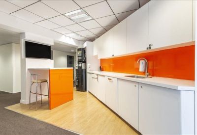 Vibrant communal kitchen with bright orange backsplash and matching breakfast bar.