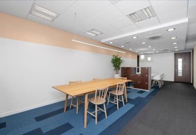 Collaborative workspace featuring a long wooden table and blue patterned flooring.
