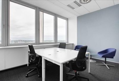 Bright four-person meeting room with large windows and blue accent chairs.