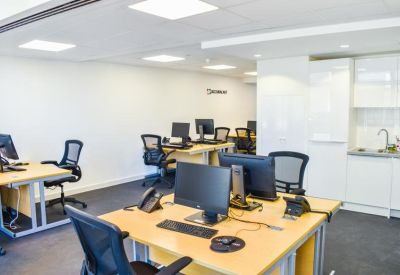 Workspace with wood-topped desks and a contemporary kitchen with white cabinetry.