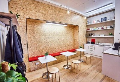 Communal kitchen and breakout area with OSB wood walls and red bench seating.