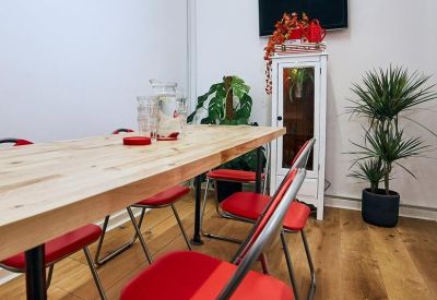 Meeting area with a long wooden table and vibrant red chairs.