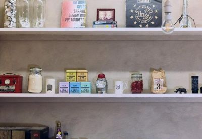 Shelving unit in a communal area stocked with various kitchen items and decor.