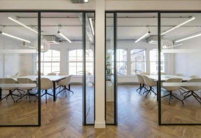 Two glass-walled meeting rooms featuring white tables and modern chairs.