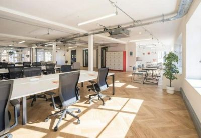 Bright open-plan workspace with chevron wood floors and white desks.