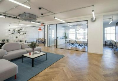 Large breakout area with a coffee table, gray sofa, and blue rug.