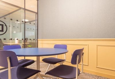 Small meeting room with a blue round table and purple chairs.