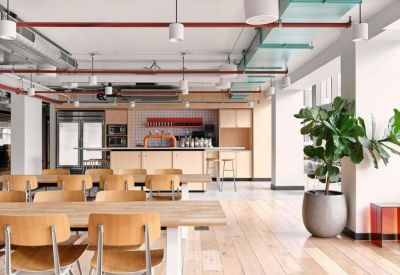 Communal dining area with wooden tables, chairs, and an industrial-style ceiling.
