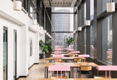 Bright, high-ceilinged coworking space with individual desks and pink desk lamps.