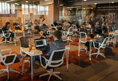 Close-up of a person working at a white desk with ergonomic chairs in a shared office.