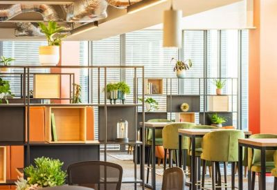 Co-working space with green velvet armchairs and high-top wooden tables.