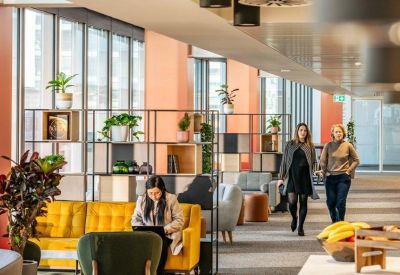 Lounge area with yellow sofa, green armchairs, and decorative shelving units with plants.