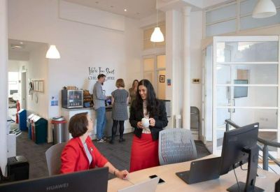 Professional reception desk area with staff, comfortable seating, and a coffee station in the background.