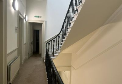 Corridor with stairs and a decorative railing.