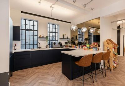 Modern kitchen with black cabinetry, white countertops, and tan leather bar stools.