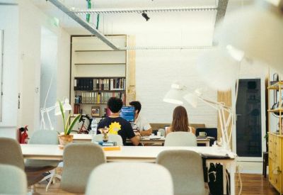 Workspace with team members at desks surrounded by bookshelves and white task lamps.
