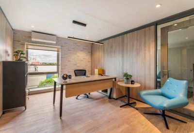 Private office suite with a large wooden desk, ergonomic chair, and comfortable blue armchair.