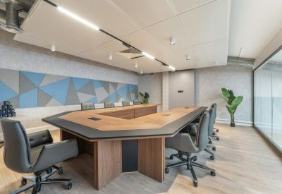 Professional boardroom with a large U-shaped wooden table and geometric wall art.