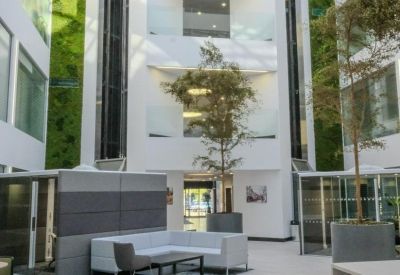 Bright multi-story atrium with living green walls, indoor trees, and white seating.