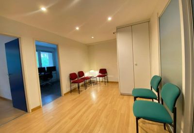 Reception and waiting area with hardwood floors, colorful chairs, and bright recessed lighting.