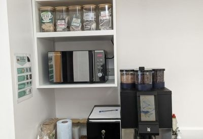 Kitchen station with a coffee machine, microwave, and stocked pantry shelves.