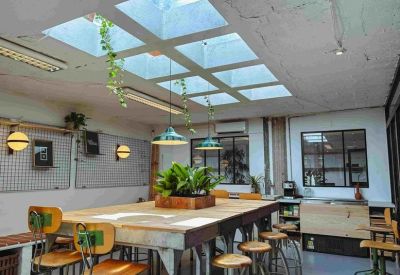 Spacious shared table with industrial stools under a bright multi-panel skylight.
