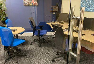 A small office space with blue chairs, glass doors, and motivational wall art.