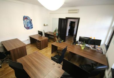 Spacious co-working office area with multiple workstations and polished wooden floors.