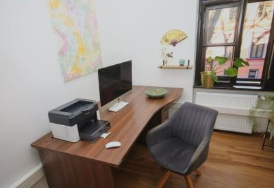 Private office suite featuring a curved wooden desk, printer, and window view.