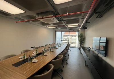 Long boardroom with a sleek wooden table and city views through floor-to-ceiling windows.