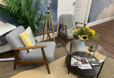 Lounge area featuring grey armchairs, a glass coffee table, and a vibrant floral arrangement.