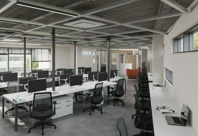 Spacious open-plan workspace with multiple white desks and industrial ceiling.