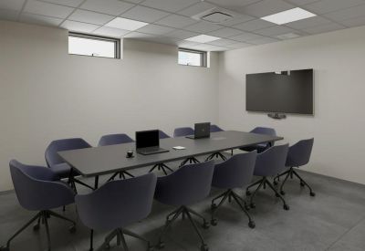 Professional meeting room with a dark conference table and wall-mounted TV.