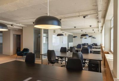 Spacious open-plan office with dark wooden desks and large black pendant lighting.