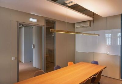 Minimalist meeting room with a wooden table, colorful chairs, and a whiteboard.