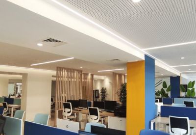 Spacious coworking area with rows of desks, a yellow feature pillar, and blue accents.