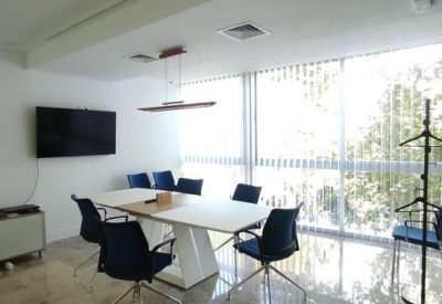 Conference room with a wall-mounted TV, white table, and minimalist storage unit.