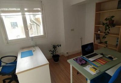 Office workspace with two white desks, blue office chairs, and wooden bookshelves.
