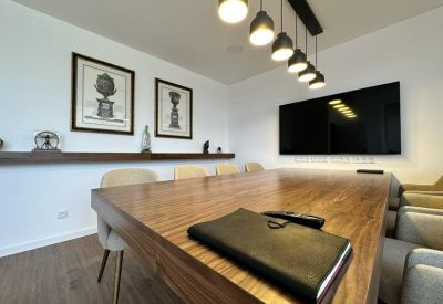 Professional meeting room featuring a polished wood table, framed art, and contemporary pendant lighting.